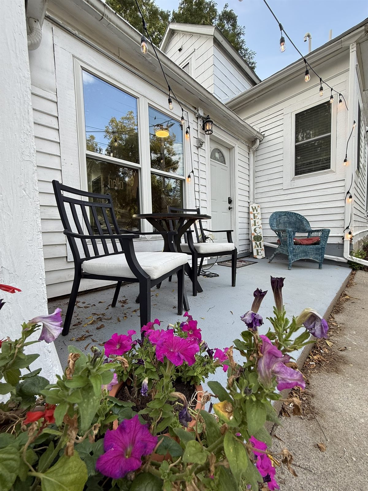 A shared string-light patio and flowers at Rose's Village